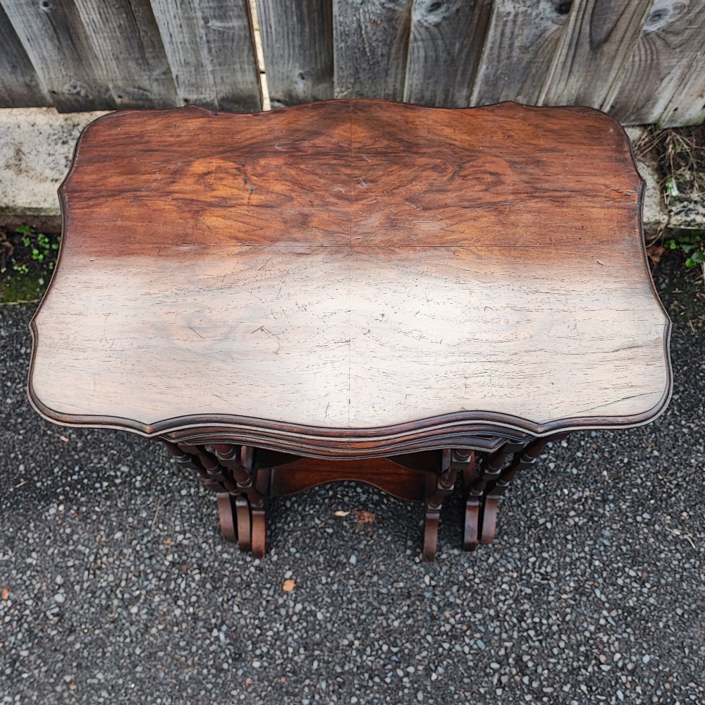 A set of three antique walnut nesting tables with serpentine edges and turned legs stacked together. View III