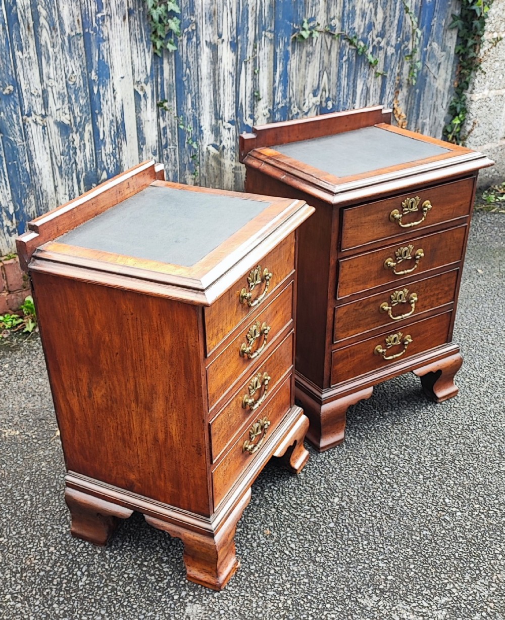 A pair of small warm brown mahogany chests of drawers featuring inset leather tops, four drawers with brass swan-neck handles, and shaped bracket feet. View IV