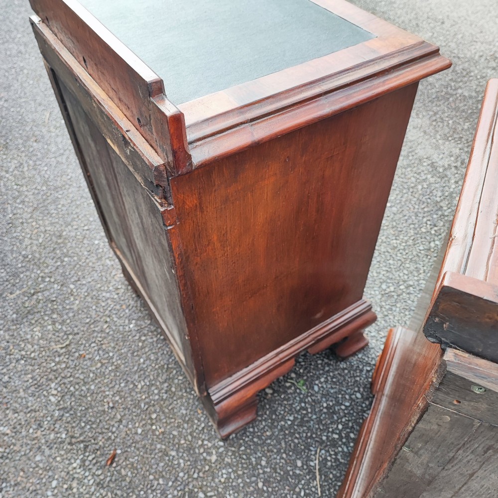 A pair of small warm brown mahogany chests of drawers featuring inset leather tops, four drawers with brass swan-neck handles, and shaped bracket feet. View V