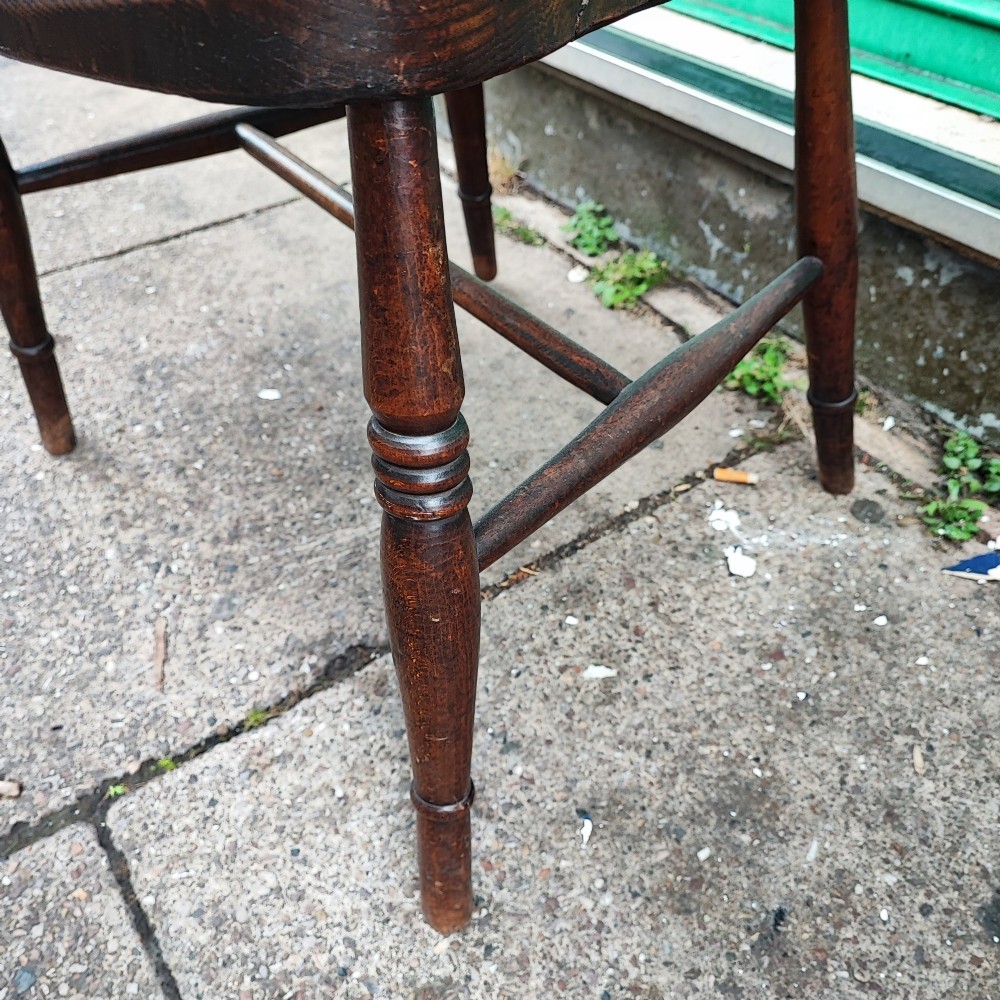 A pair of antique wooden Windsor armchairs featuring pierced wheelback splats, curved arms, shaped saddle seats, and turned legs. View IV