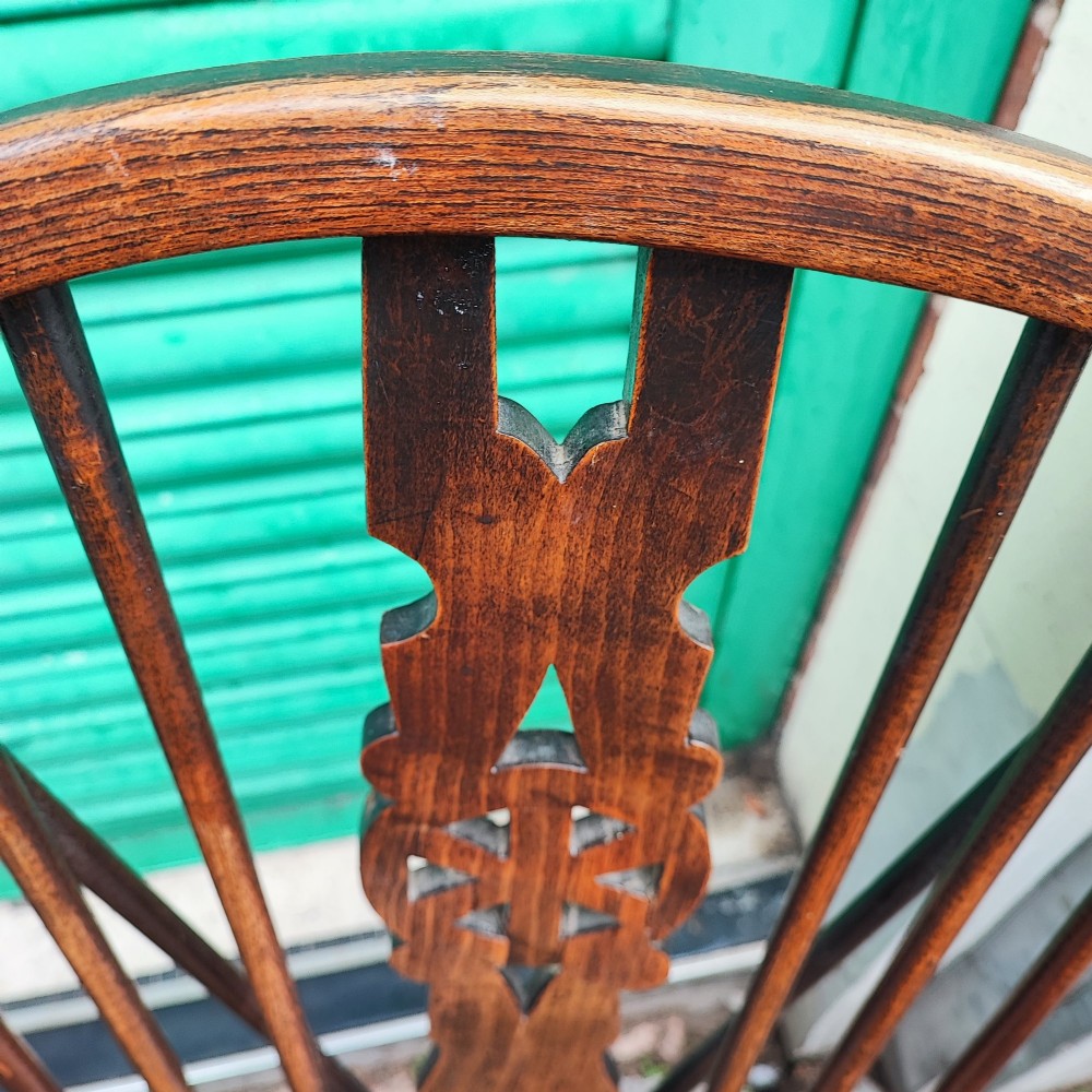 A pair of antique wooden Windsor armchairs featuring pierced wheelback splats, curved arms, shaped saddle seats, and turned legs. View V