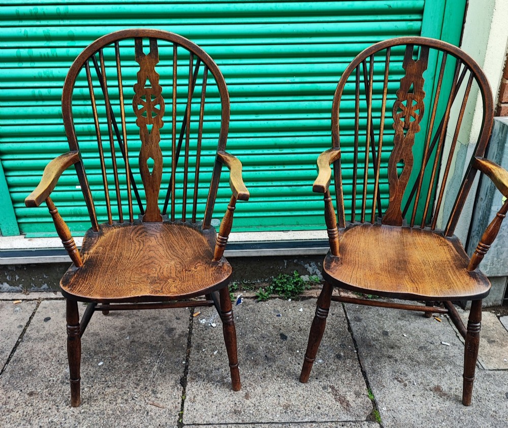 A pair of antique wooden Windsor armchairs featuring pierced wheelback splats, curved arms, shaped saddle seats, and turned legs. View VII
