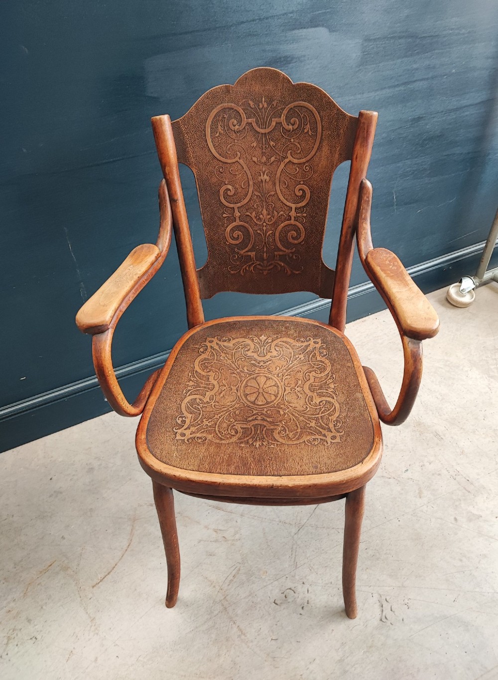 A bentwood beechwood armchair featuring curved armrests and embossed Art Nouveau scrollwork on the plywood seat and backrest. View II