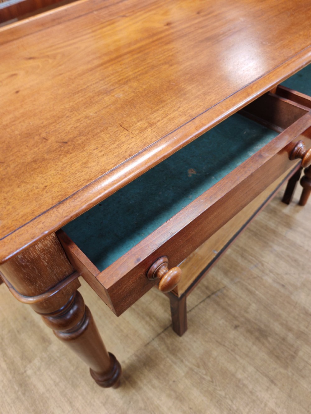 A Victorian mahogany writing table featuring a rectangular top with a low raised edge, two frieze drawers with turned wooden knobs, and turned legs. View III