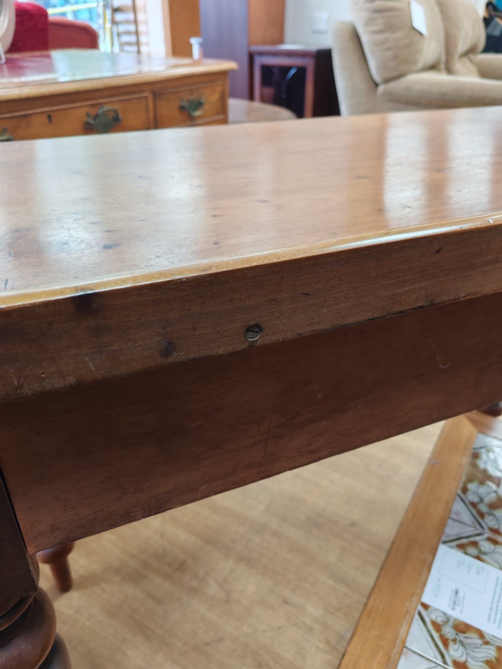A Victorian mahogany writing table featuring a rectangular top with a low raised edge, two frieze drawers with turned wooden knobs, and turned legs. View IV