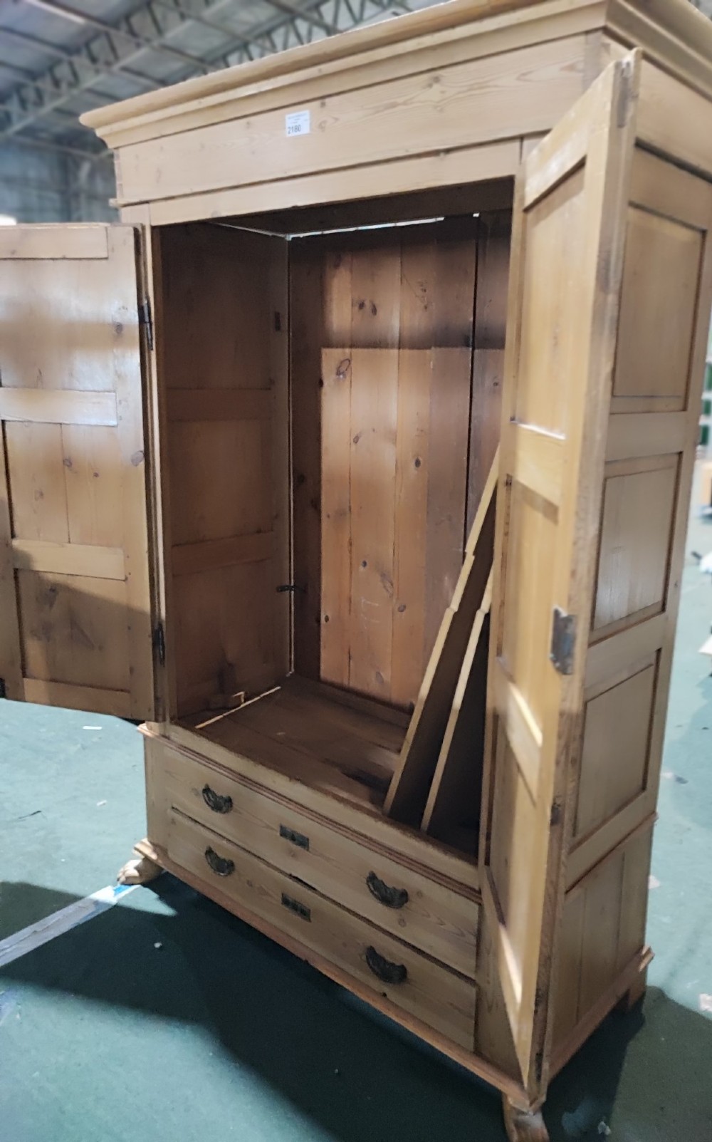 A tall antique pine two-door wardrobe featuring raised fielded panels, a moulded cornice, and two drawers at the base. View III