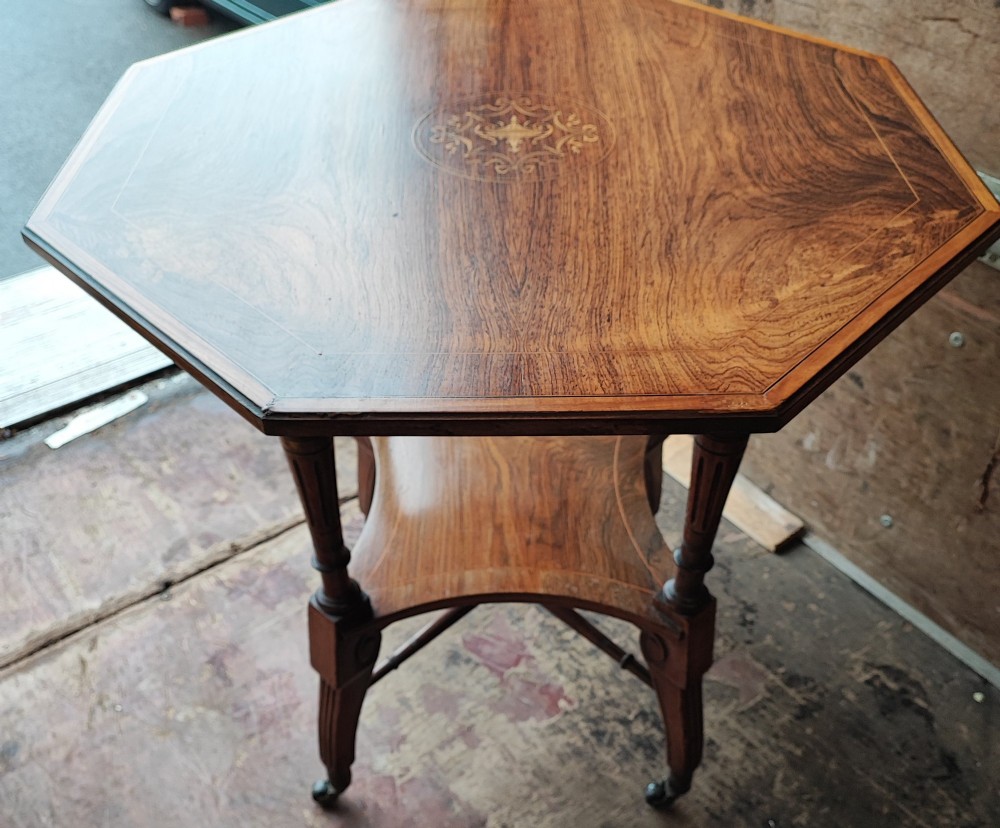 An octagonal Victorian rosewood occasional table with central marquetry inlay, slender turned legs, a lower undertier, and brass castors. View III