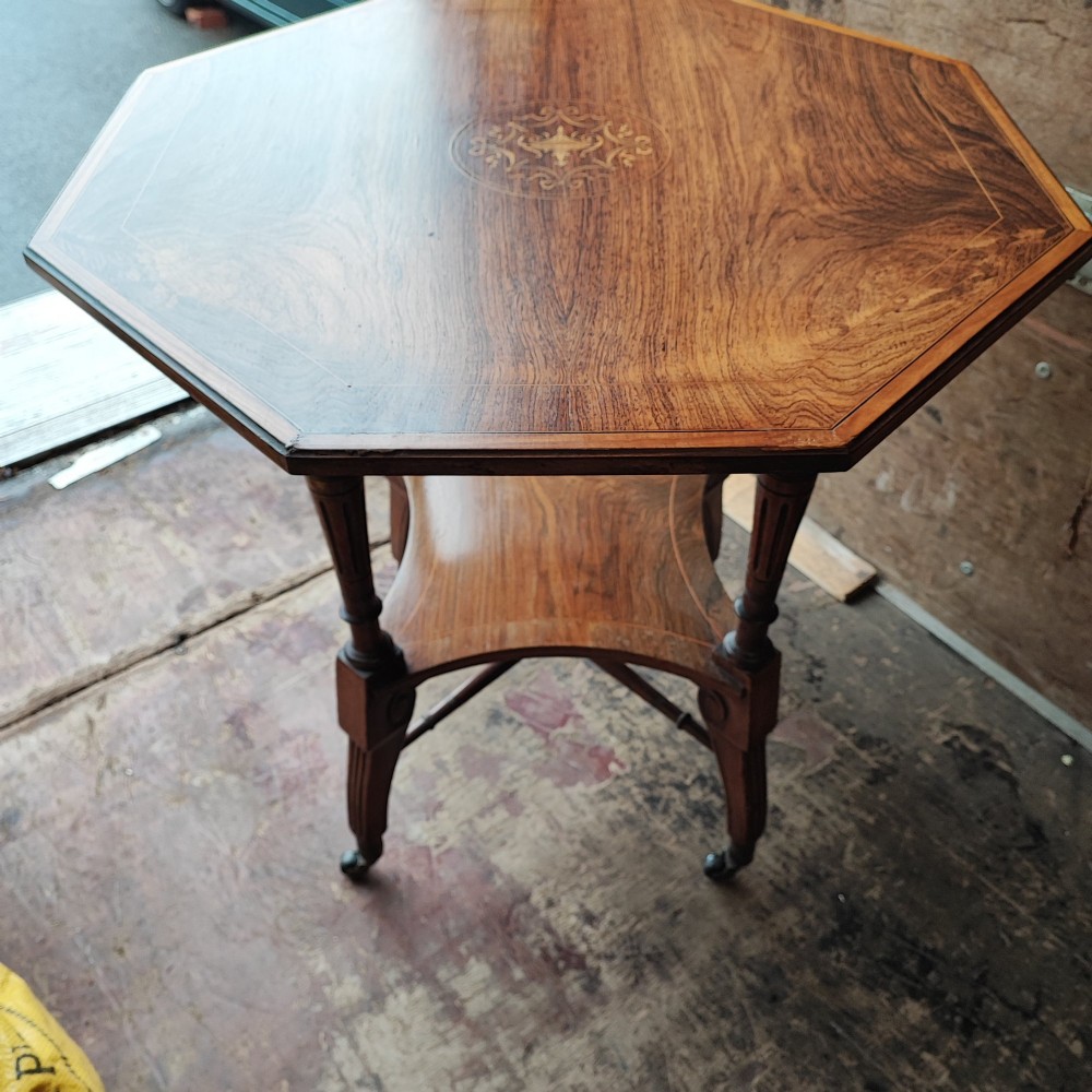 An octagonal Victorian rosewood occasional table with central marquetry inlay, slender turned legs, a lower undertier, and brass castors. View IV