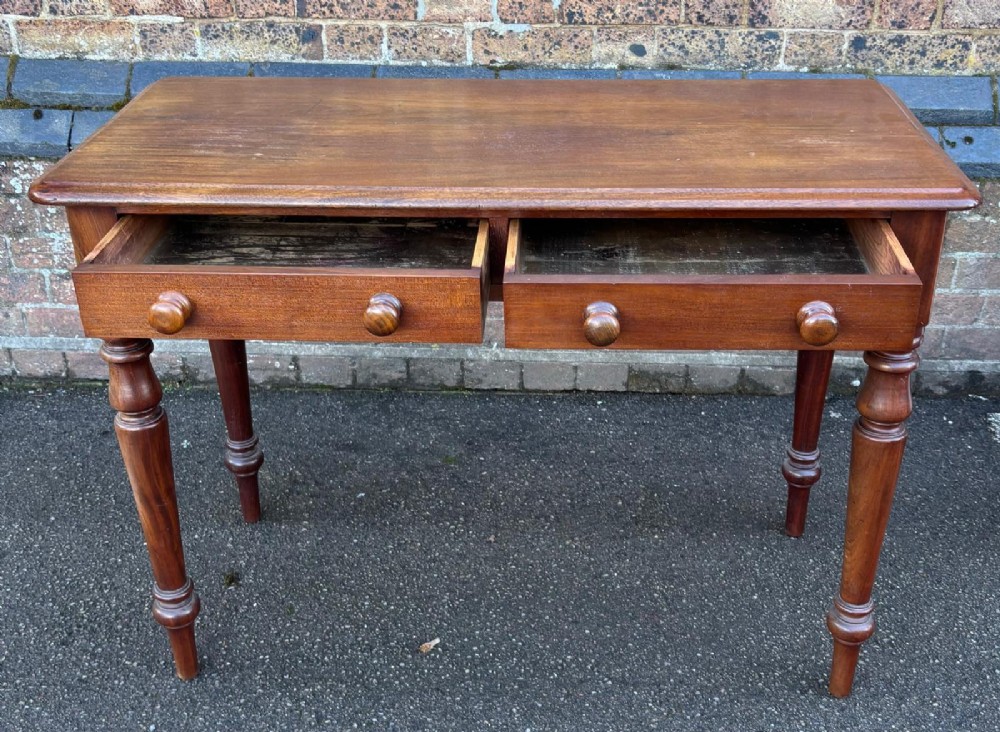 A Victorian mahogany writing table featuring a rectangular top, two front drawers with turned wooden knob handles, and four turned legs. View II