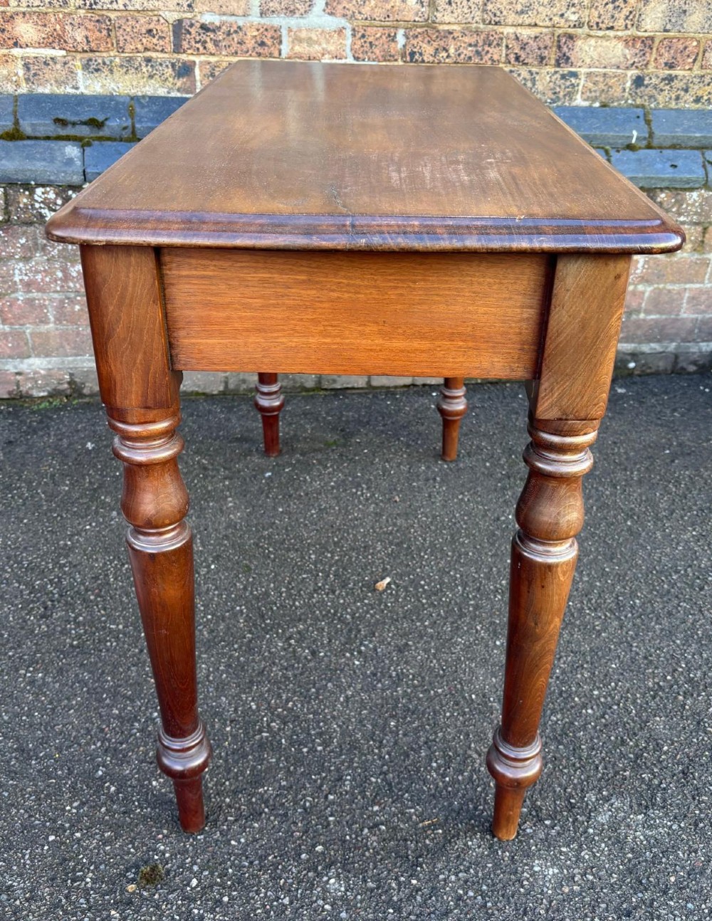 A Victorian mahogany writing table featuring a rectangular top, two front drawers with turned wooden knob handles, and four turned legs. View III