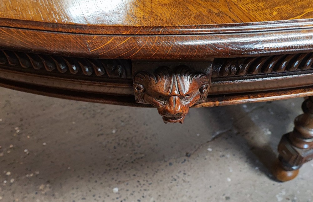 A large Victorian golden oak extending dining table featuring an oval top, carved rope-twist frieze, and elaborate turned legs joined by a central stretcher. View III