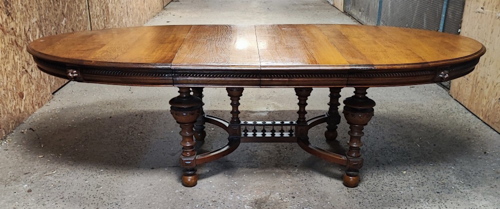 A large Victorian golden oak extending dining table featuring an oval top, carved rope-twist frieze, and elaborate turned legs joined by a central stretcher. View IV