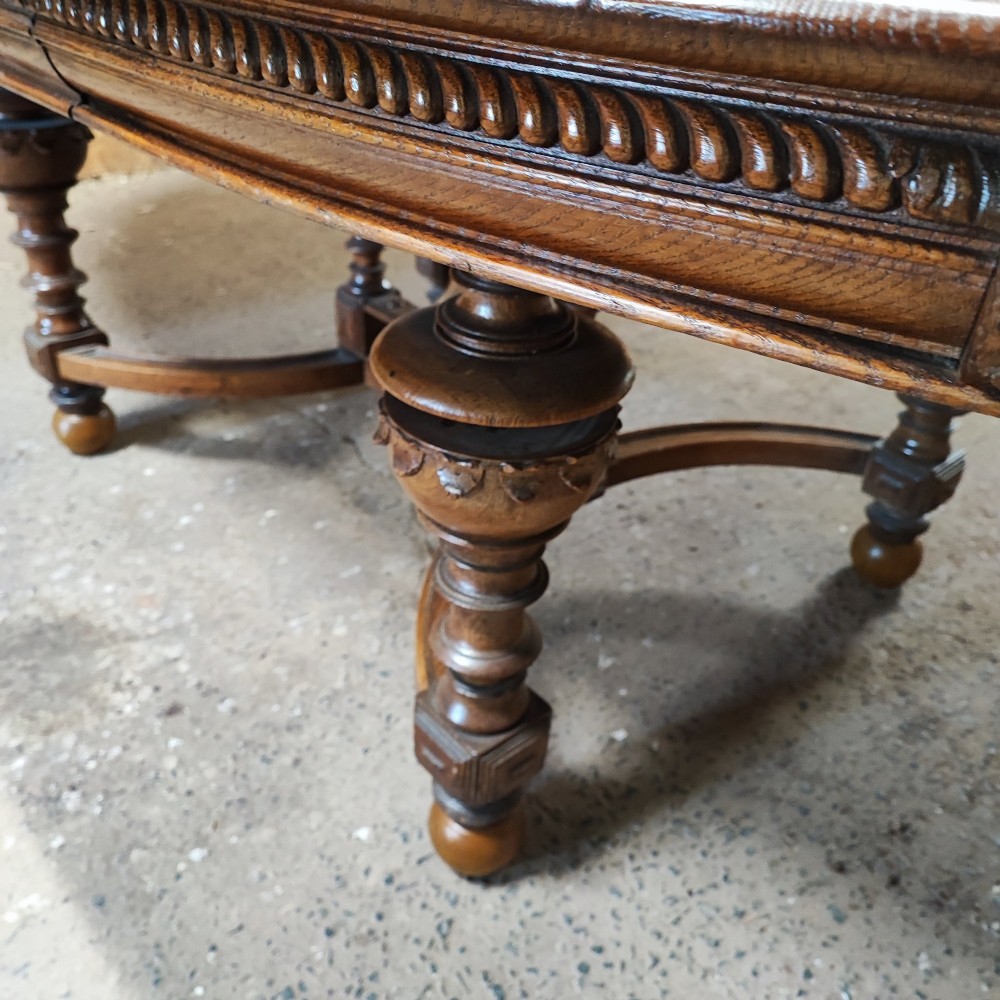 A large Victorian golden oak extending dining table featuring an oval top, carved rope-twist frieze, and elaborate turned legs joined by a central stretcher. View V