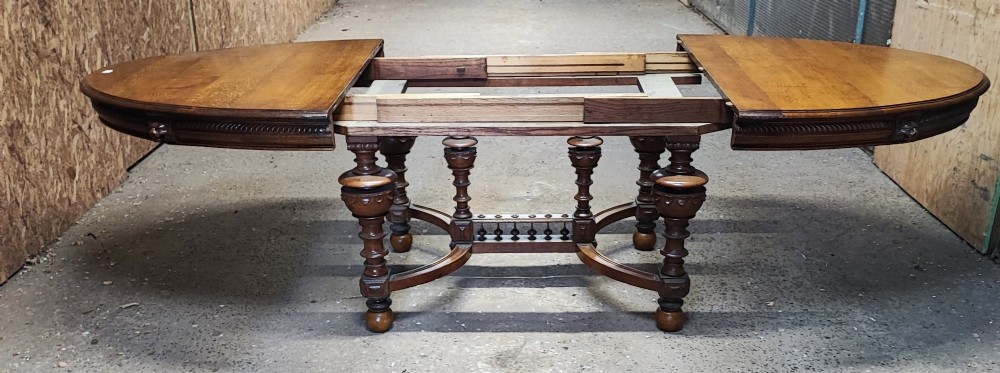 A large Victorian golden oak extending dining table featuring an oval top, carved rope-twist frieze, and elaborate turned legs joined by a central stretcher. View X