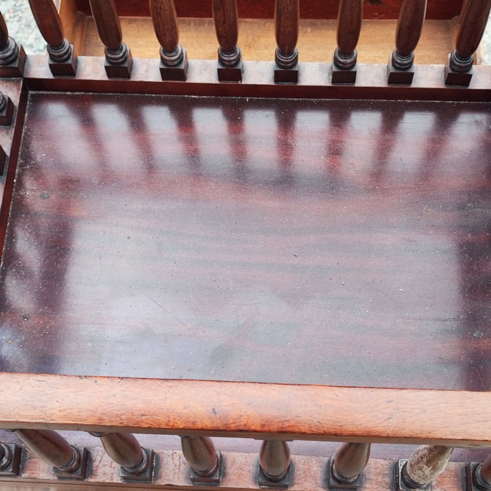 An antique Regency mahogany book trough with turned spindle sides, a single lower drawer with brass handles, and turned legs supported on brass castors. View IV