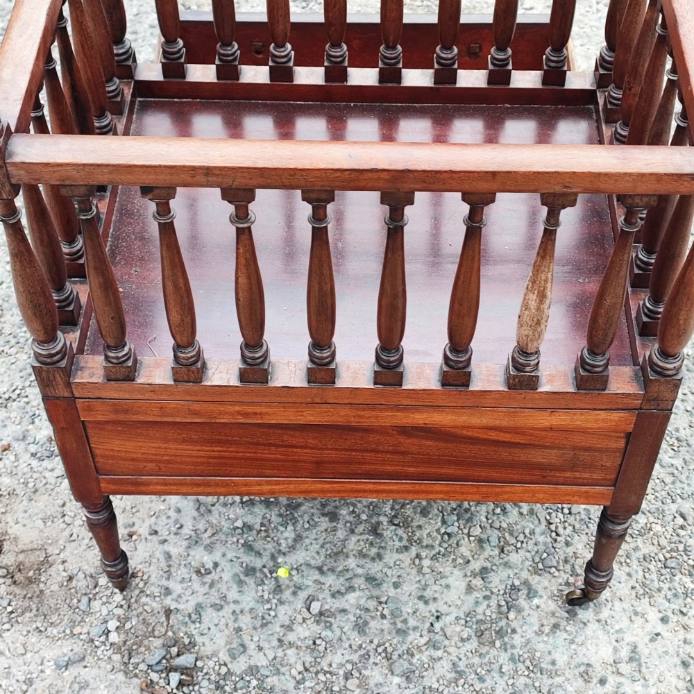 An antique Regency mahogany book trough with turned spindle sides, a single lower drawer with brass handles, and turned legs supported on brass castors. View V
