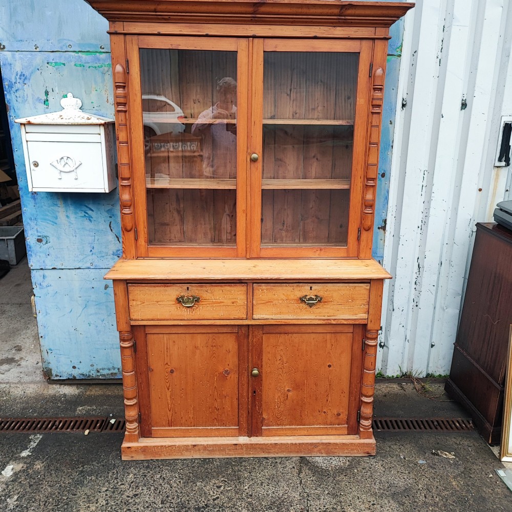 A two-piece stripped pine dresser featuring a glazed upper display cabinet with two doors and a lower section with two drawers above twin cupboard doors. View VI