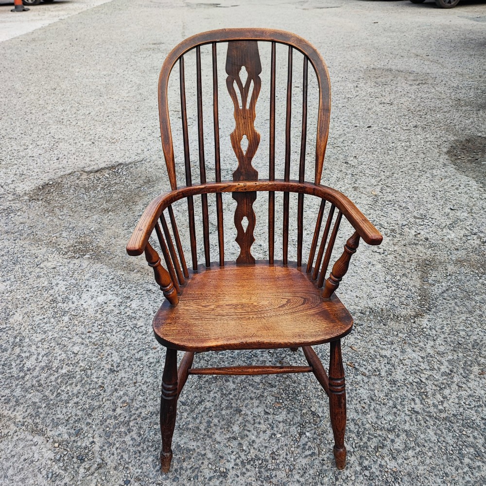 An antique dark brown wooden Windsor armchair featuring a steam-bent hoop back, a decorative pierced central splat, turned spindles, and a shaped elm seat. View II