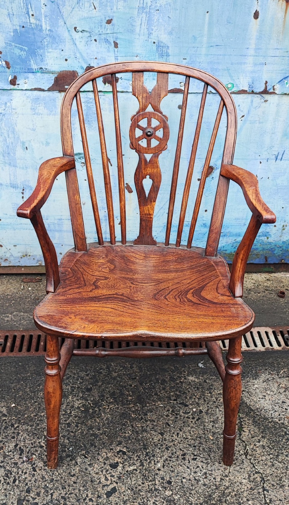 An antique Windsor armchair crafted from warm brown elm and fruitwood with a wheelback splat, hoop back, contoured seat, and turned legs.
