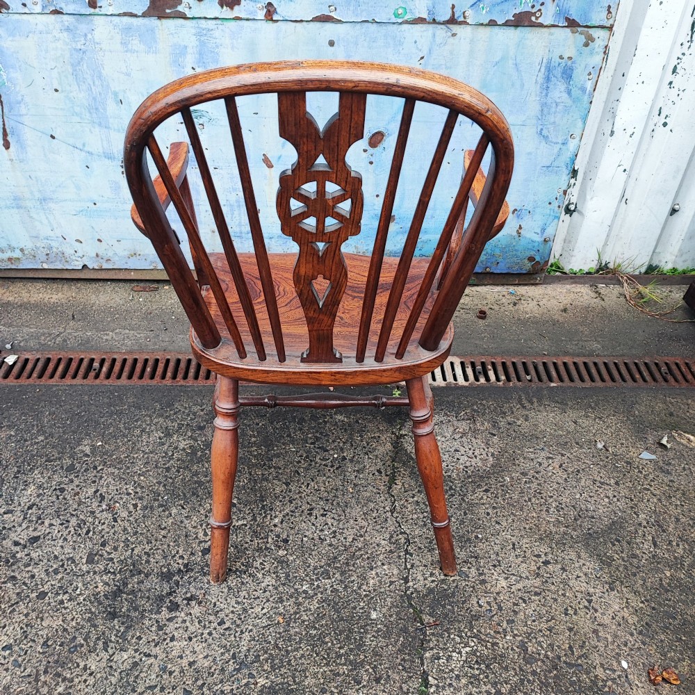 An antique Windsor armchair crafted from warm brown elm and fruitwood with a wheelback splat, hoop back, contoured seat, and turned legs. View III