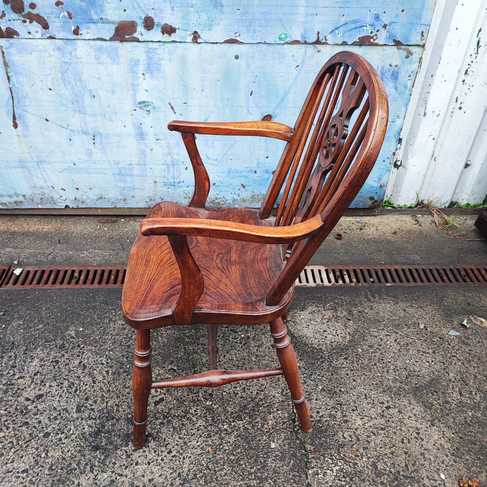 An antique Windsor armchair crafted from warm brown elm and fruitwood with a wheelback splat, hoop back, contoured seat, and turned legs. View IV