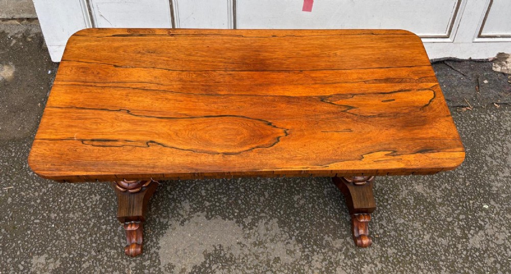 A rectangular antique rosewood window table featuring a highly figure-grained top, a scalloped frieze with drop pendants, and twin carved pedestal supports on lotus trestle feet. View II