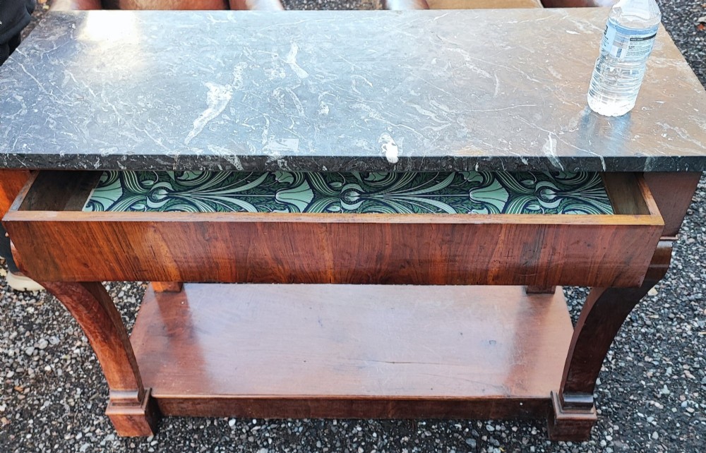 An antique French walnut console table featuring a thick grey veined marble top, scrolled front supports, and a lower plinth undertier. View IV