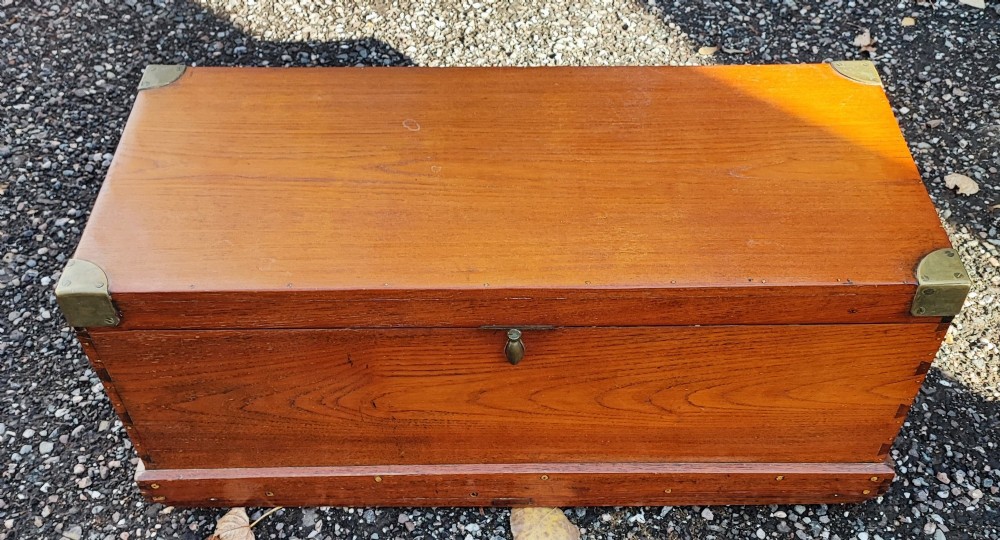 A rectangular warm brown teak sea chest featuring reinforced brass corner brackets and dovetail joinery. View II