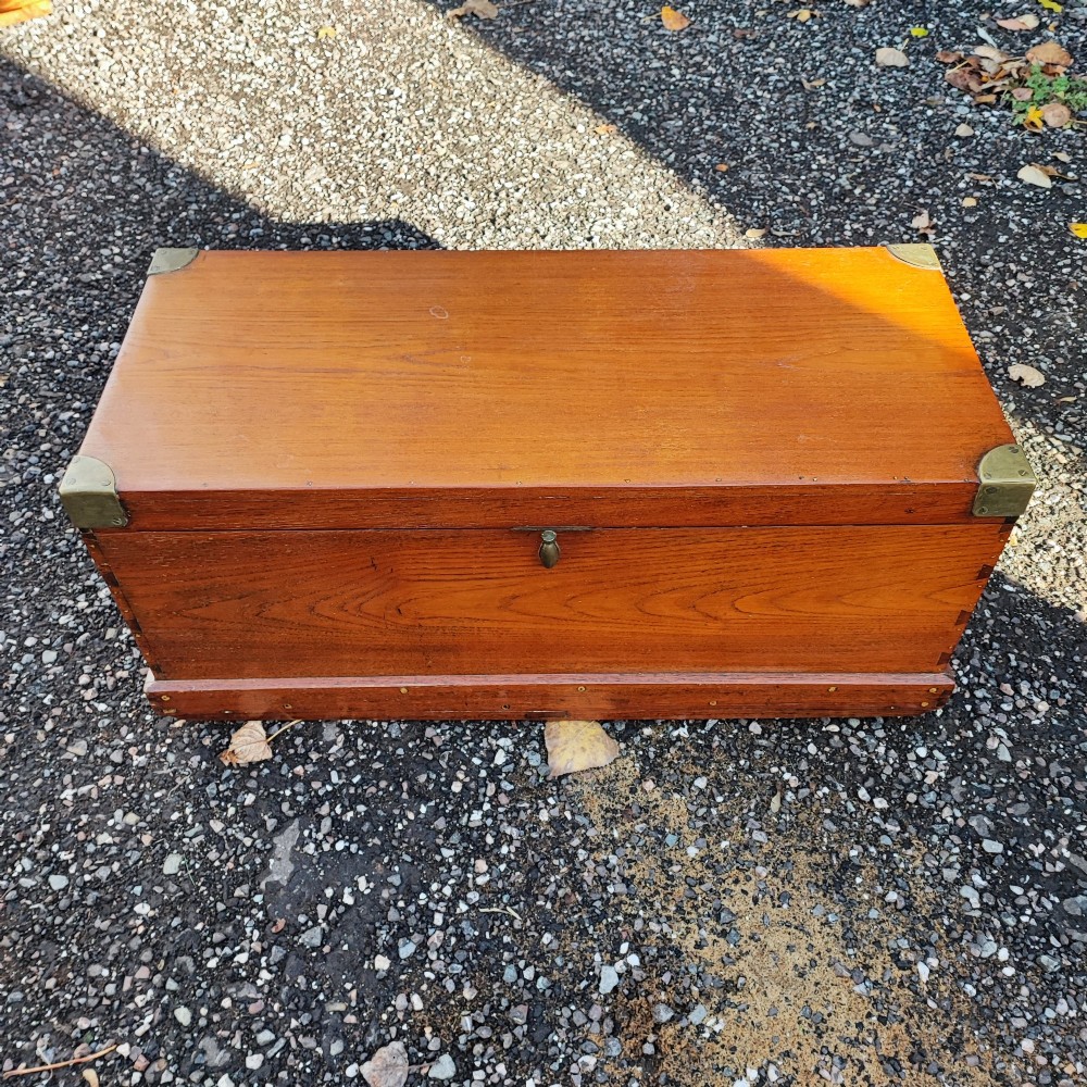 A rectangular warm brown teak sea chest featuring reinforced brass corner brackets and dovetail joinery. View III