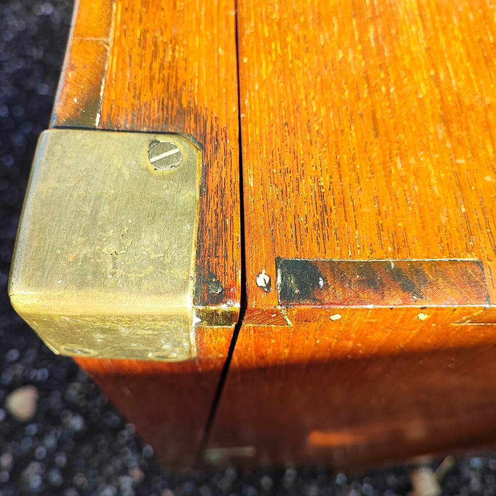A rectangular warm brown teak sea chest featuring reinforced brass corner brackets and dovetail joinery. View IX