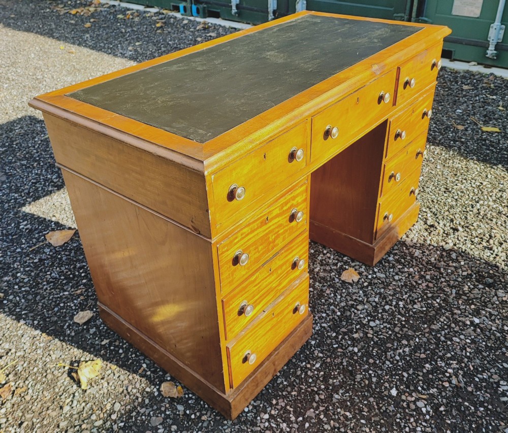 An antique blonde mahogany pedestal kneehole desk with a dark leather writing surface insert and nine drawers fitted with brass knob handles. View VI