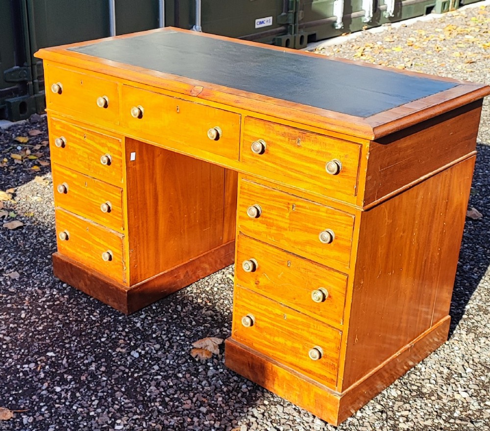 An antique blonde mahogany pedestal kneehole desk with a dark leather writing surface insert and nine drawers fitted with brass knob handles. View VII