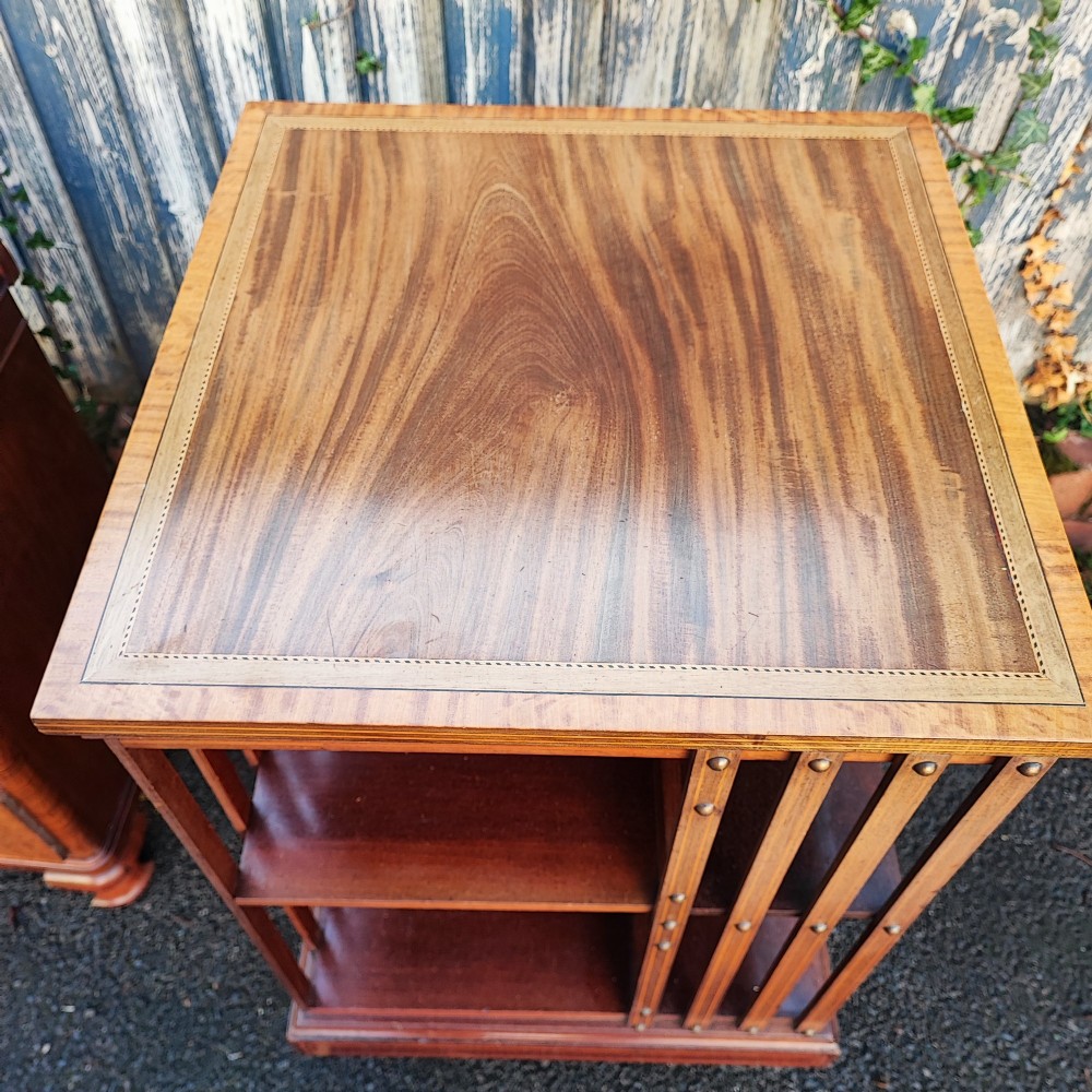 An Edwardian style square mahogany revolving bookcase featuring fine marquetry inlay along the top surface and vertical slatted sides accented with brass studs. View II