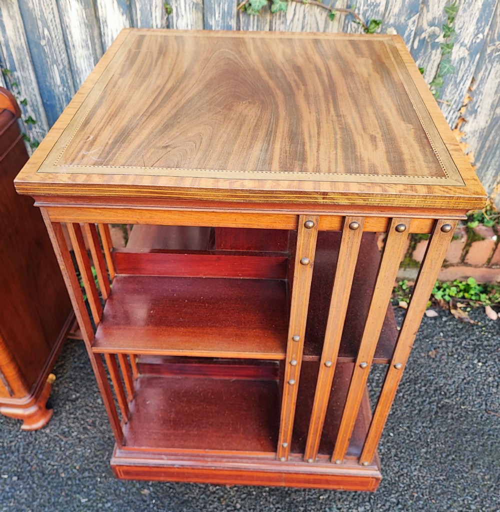 An Edwardian style square mahogany revolving bookcase featuring fine marquetry inlay along the top surface and vertical slatted sides accented with brass studs. View III