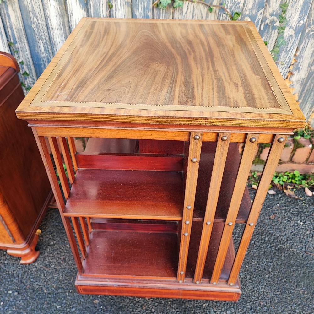 An Edwardian style square mahogany revolving bookcase featuring fine marquetry inlay along the top surface and vertical slatted sides accented with brass studs. View VI