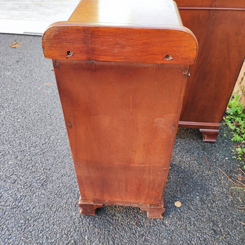 A pair of matching Art Deco burr walnut bedside cabinets featuring three drawers with carved wooden handles and a low raised gallery top. View VII