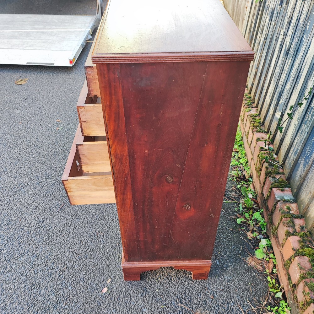 A tall, narrow mahogany chest of six drawers with circular brass ring pulls, flame veneer drawer fronts, and bracket feet. View IV