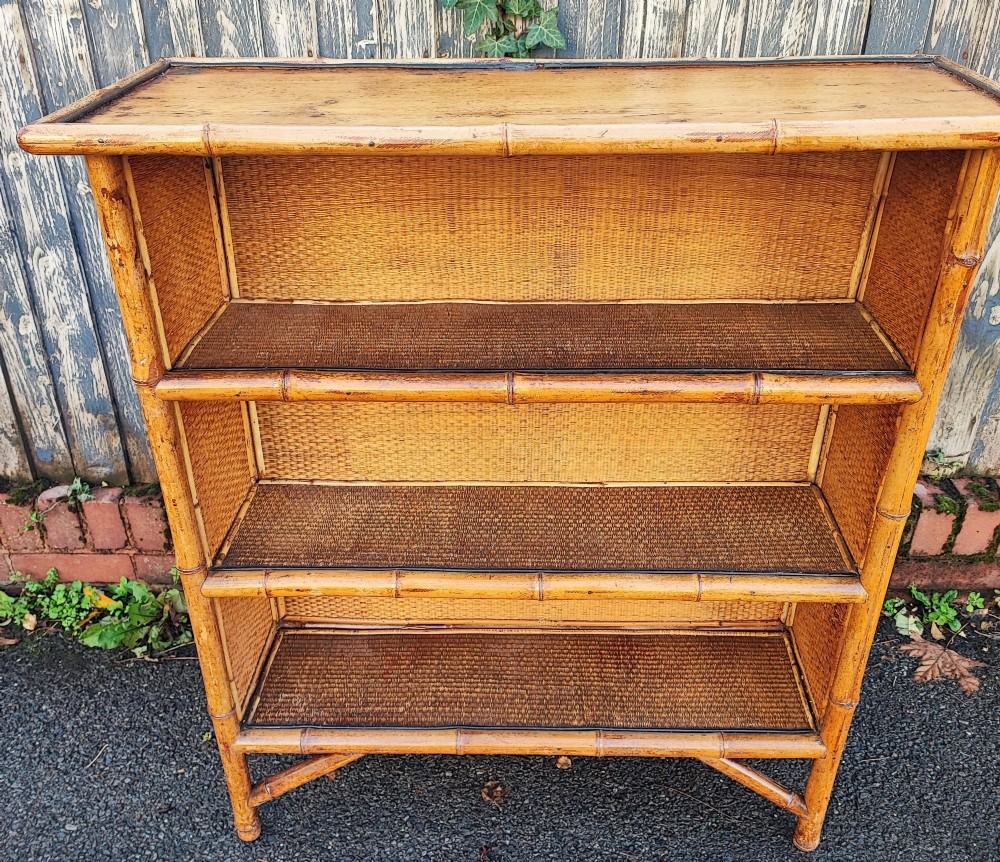 A late Victorian open bookcase featuring a bamboo cane frame, pine side panels, and three woven cane display shelves. View V