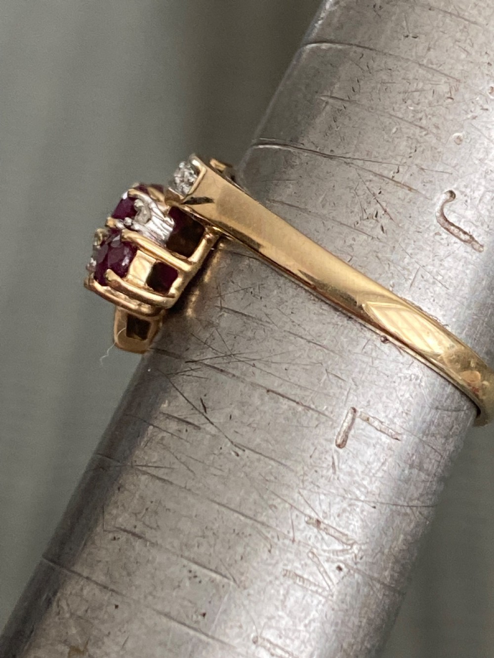 A vintage yellow gold dress ring featuring multiple oval cut rubies alongside small diamond accents set within curved gold rails. View II