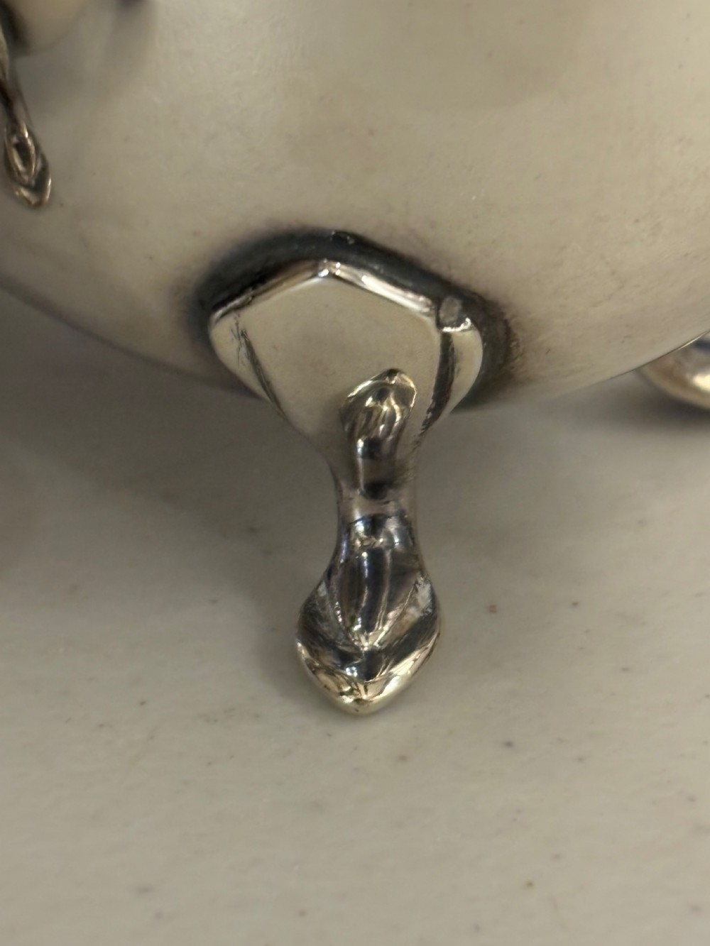 A matching pair of polished sterling silver sauceboats with flying scroll handles, scalloped rims, and tripod pad feet. View V