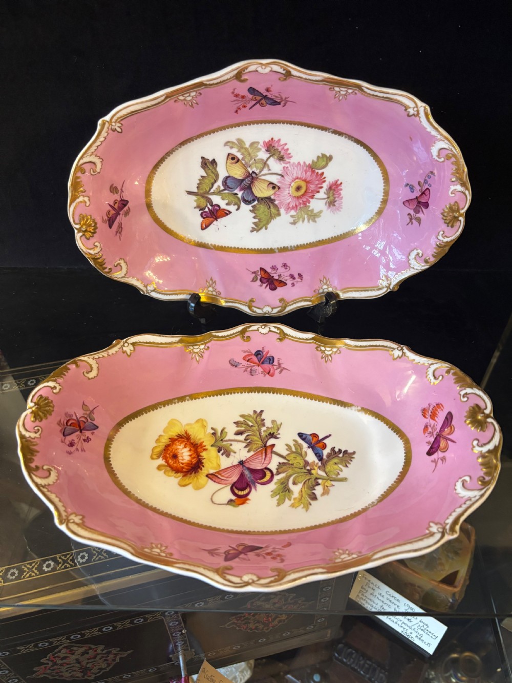 A pair of oval Georgian Spode porcelain dishes featuring scalloped pink and gold borders surrounding central hand-painted floral and butterfly motifs. View XI