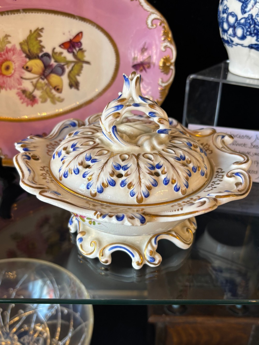 An 18th-century white porcelain pomander featuring a pierced lattice cover, elaborate blue and gold scrollwork, and a shaped pedestal base. View VI