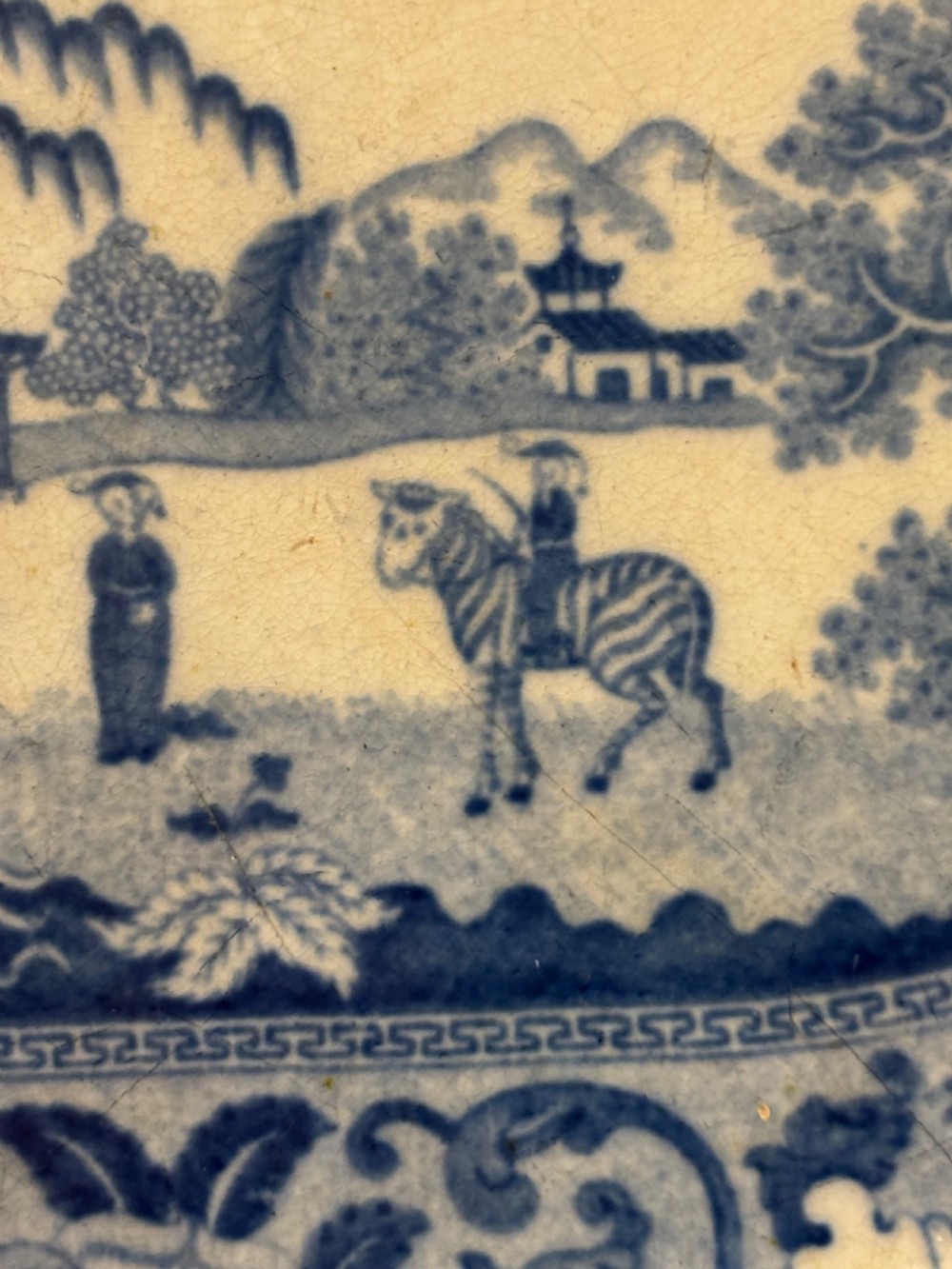 An oval Georgian earthenware platter featuring a cobalt blue transfer-printed exotic landscape with a zebra motif, surrounded by a floral border. View II