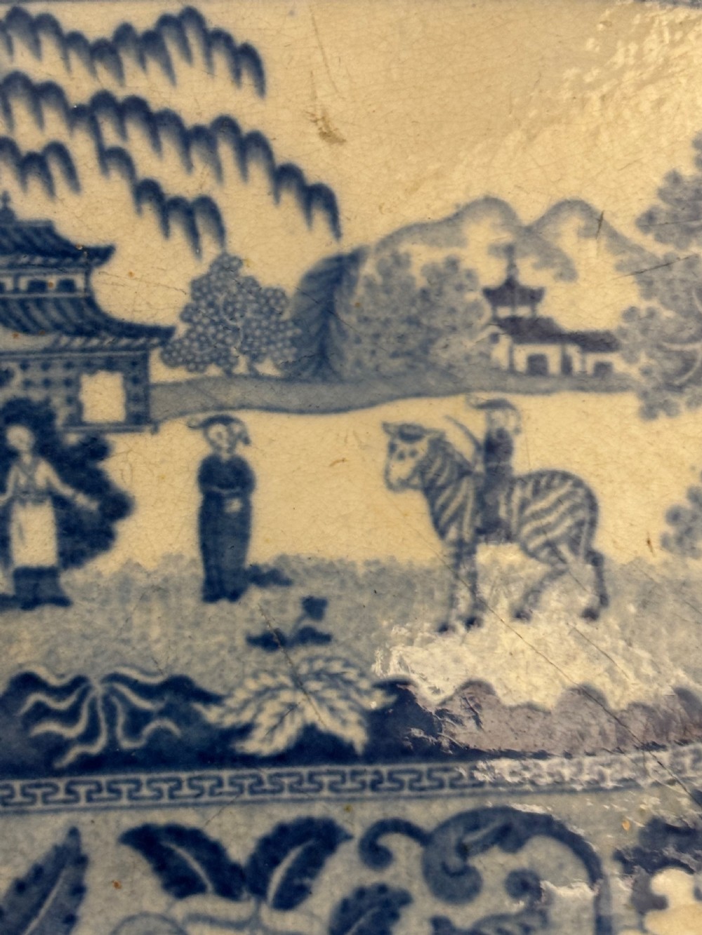 An oval Georgian earthenware platter featuring a cobalt blue transfer-printed exotic landscape with a zebra motif, surrounded by a floral border. View III