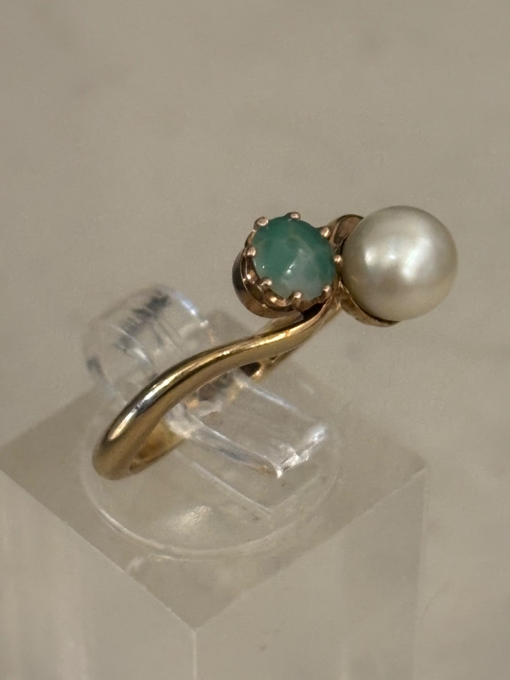 A yellow gold bypass ring featuring a round white cultured pearl alongside a claw-set green jade cabochon. View II