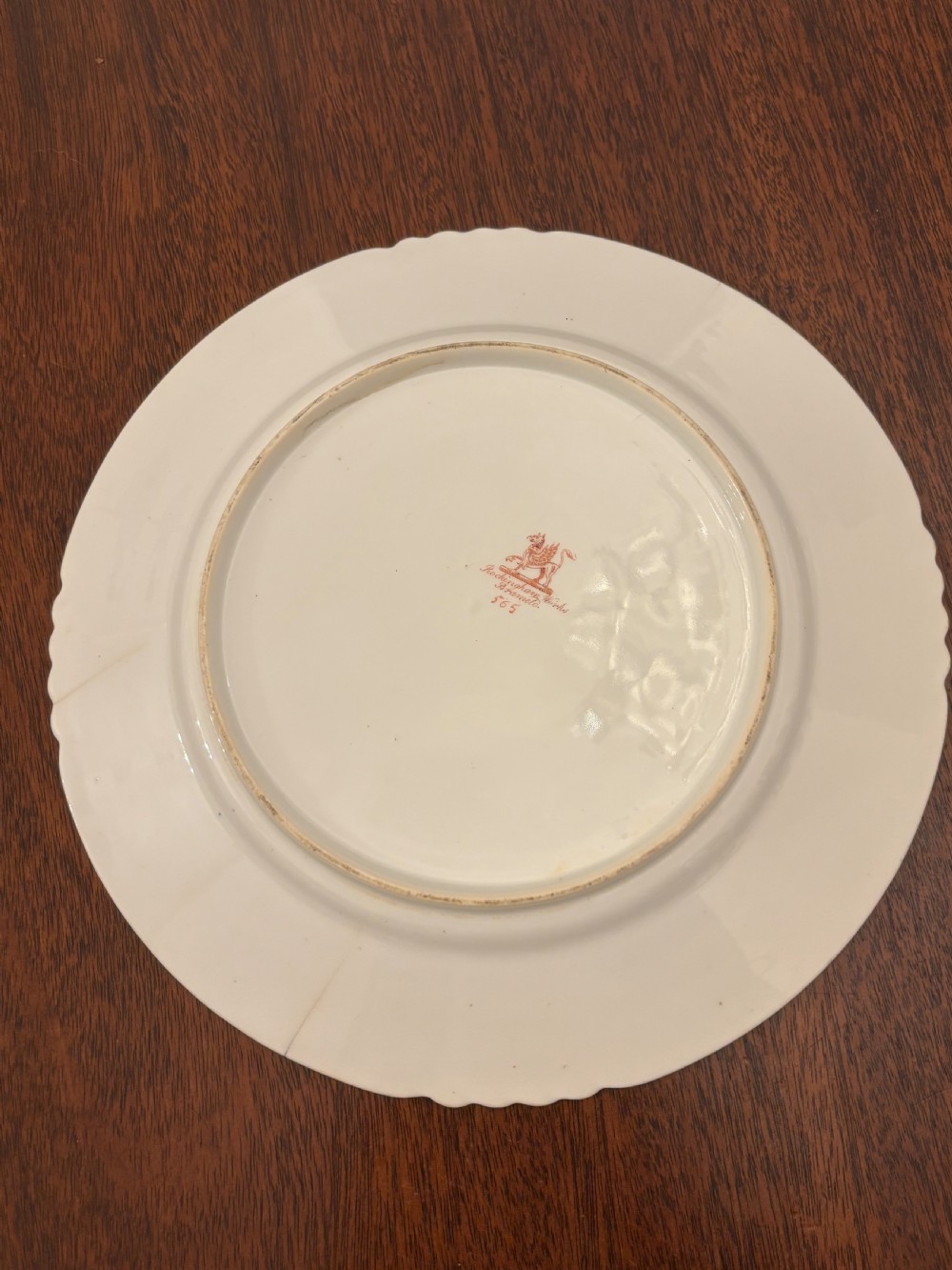 An antique off-white porcelain dessert service with hand-painted floral sprigs, scalloped edges, and gilded rims arranged against a black backdrop. View VIII