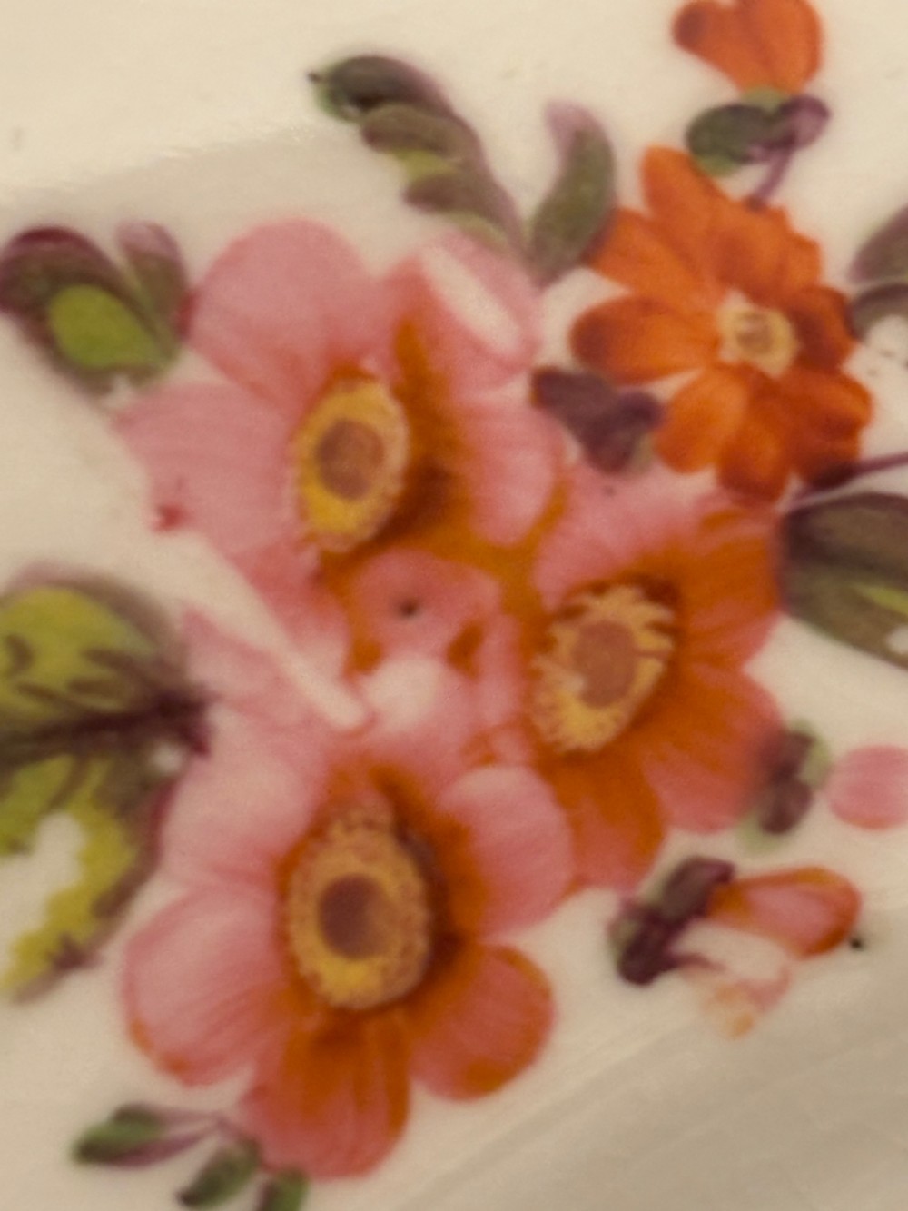 An antique off-white porcelain dessert service with hand-painted floral sprigs, scalloped edges, and gilded rims arranged against a black backdrop. View XIII