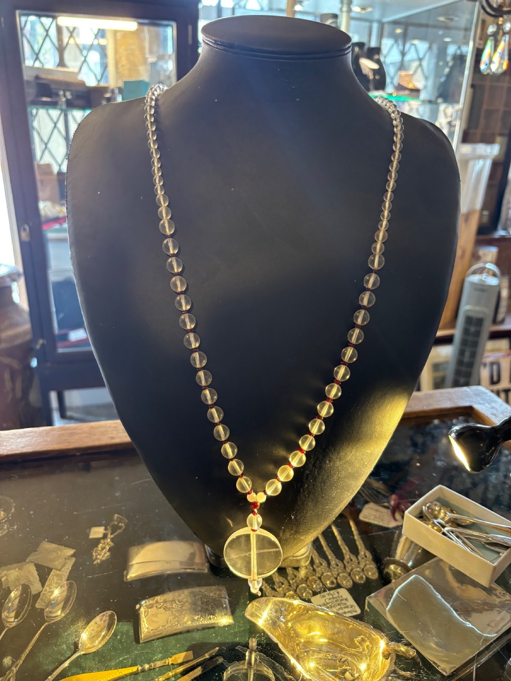 An Art Deco necklace composed of clear spherical rock crystal beads ending with a large round crystal disc pendant. View IX