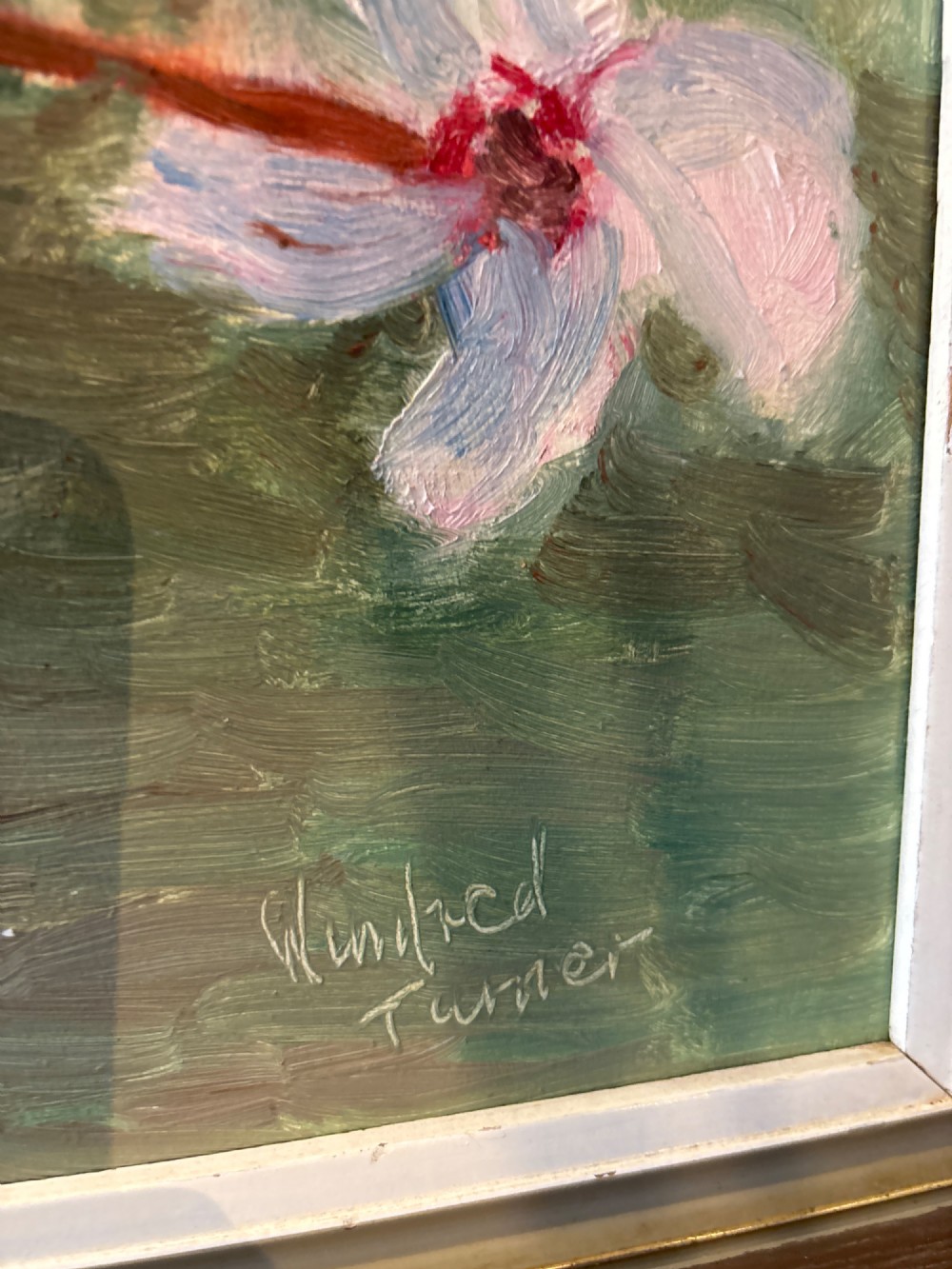 A framed mid-century oil painting on board depicting white and pink cyclamen flowers in a glass vase against a sage green background, signed by artist Winifred Turner. View II