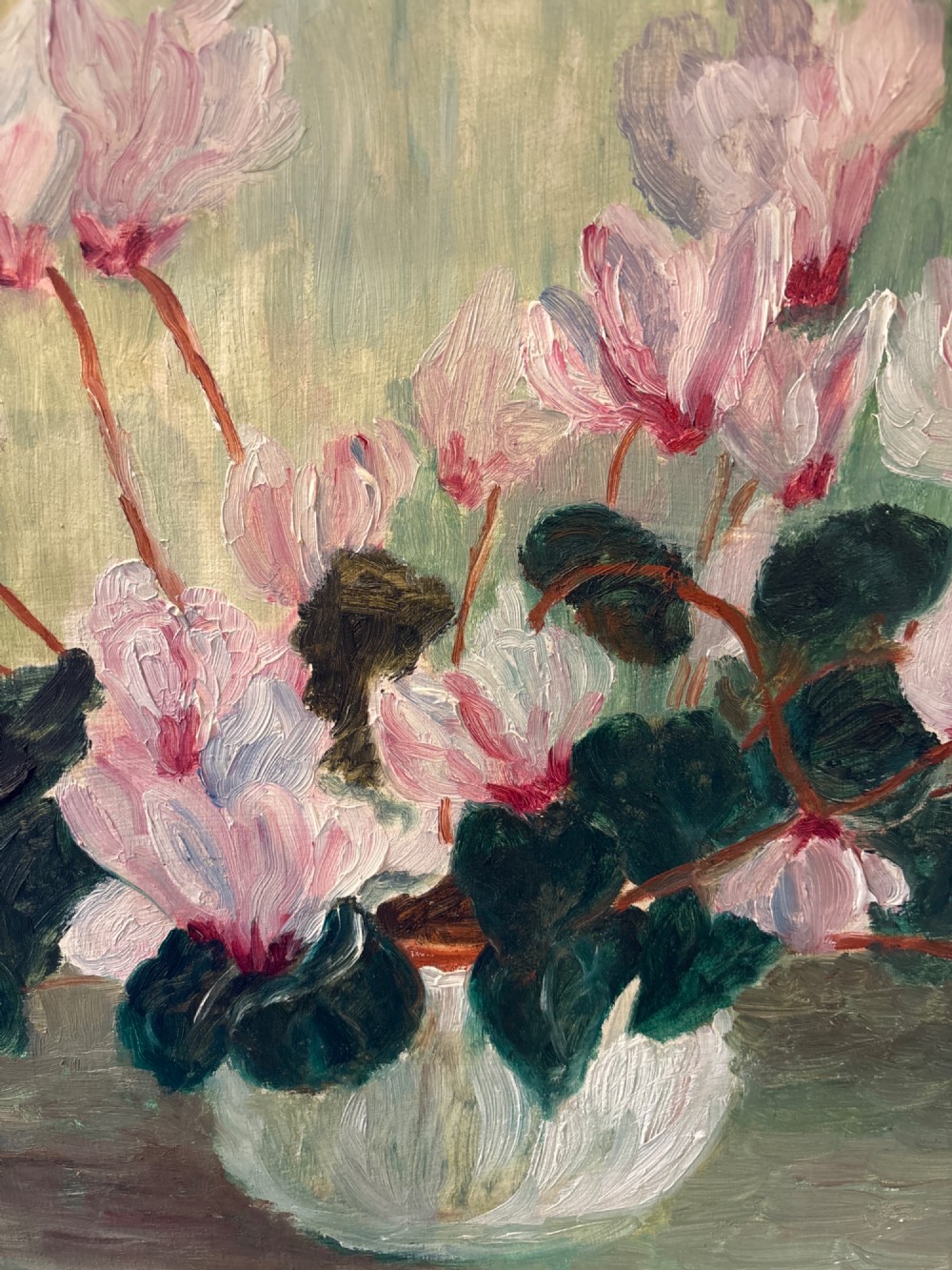 A framed mid-century oil painting on board depicting white and pink cyclamen flowers in a glass vase against a sage green background, signed by artist Winifred Turner. View III